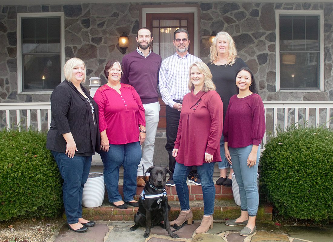 About Our Agency - Smiling Portrait of the JPI Insurance Associates Team Standing Outside the Office with Their Dog on a Sunny Day